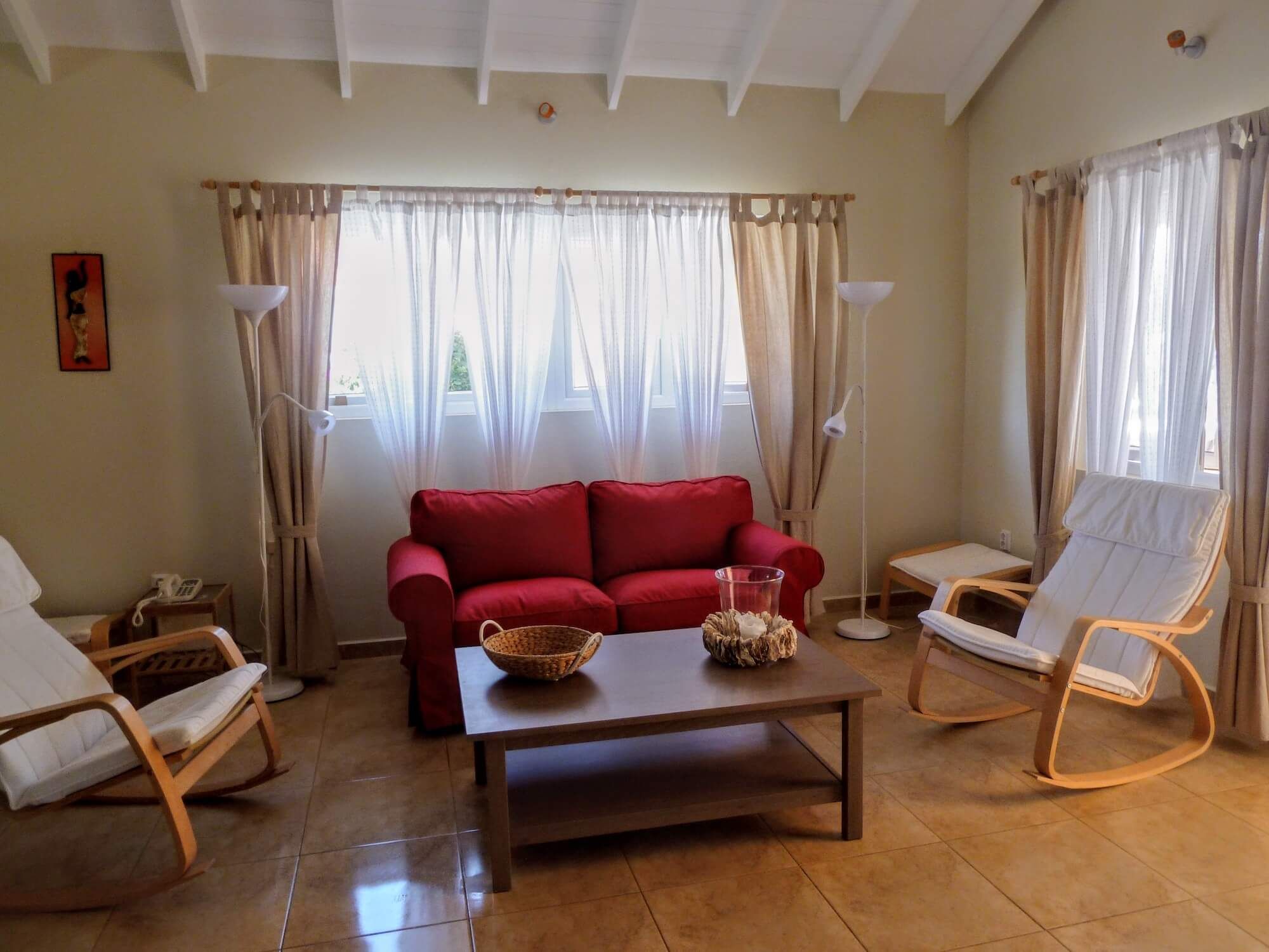The living room with a red sofa, wooden coffee table and high white ceilings