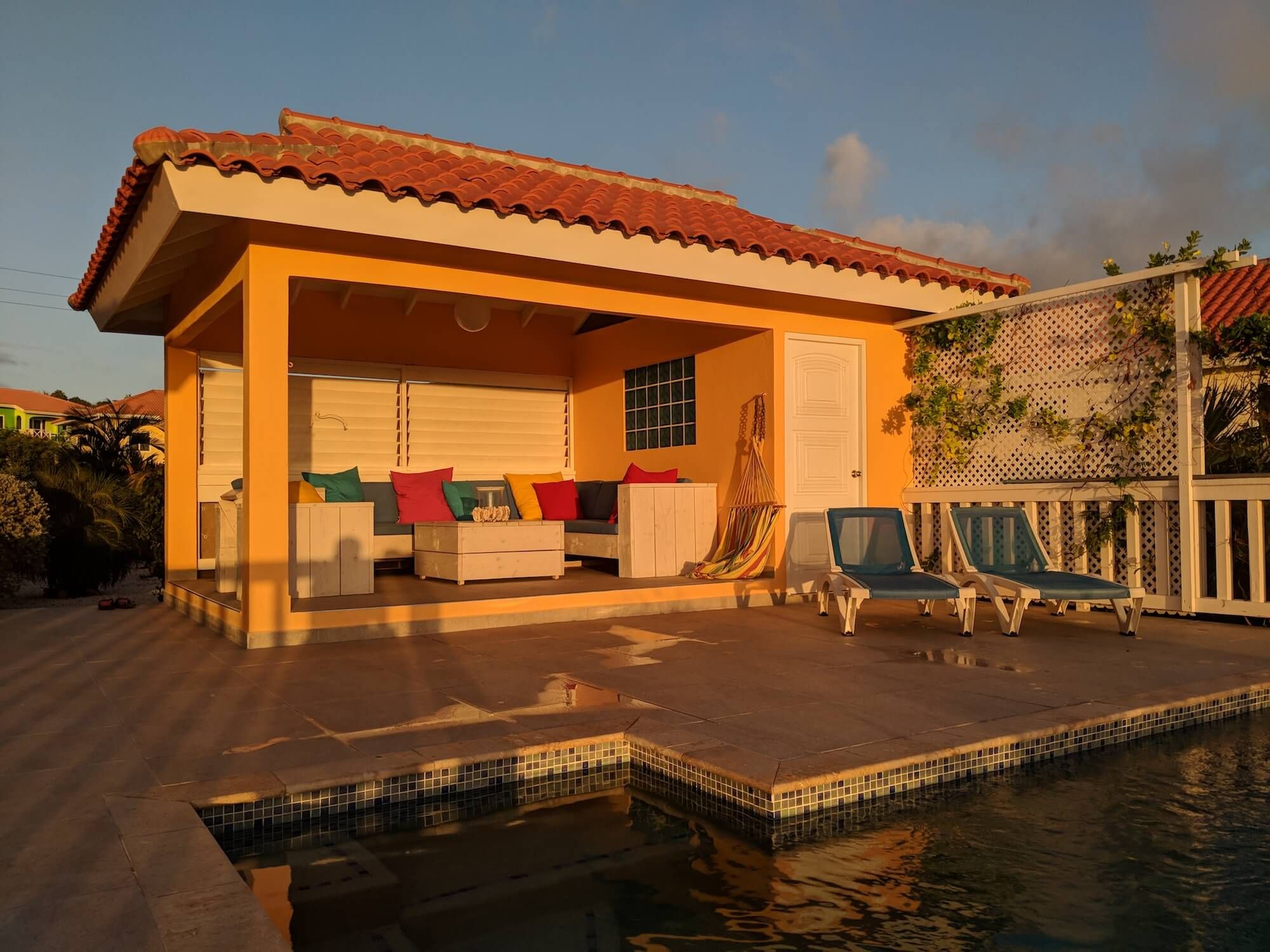 Die überdachte Lounge-Veranda neben dem Pool im Licht der untergehenden Sonne
