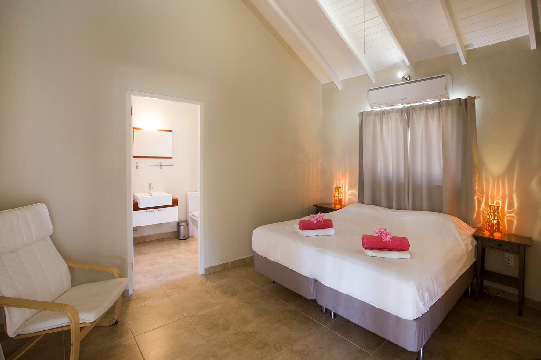 The master bedroom with double bed, towels on the bed and the door to the en-suite bathroom