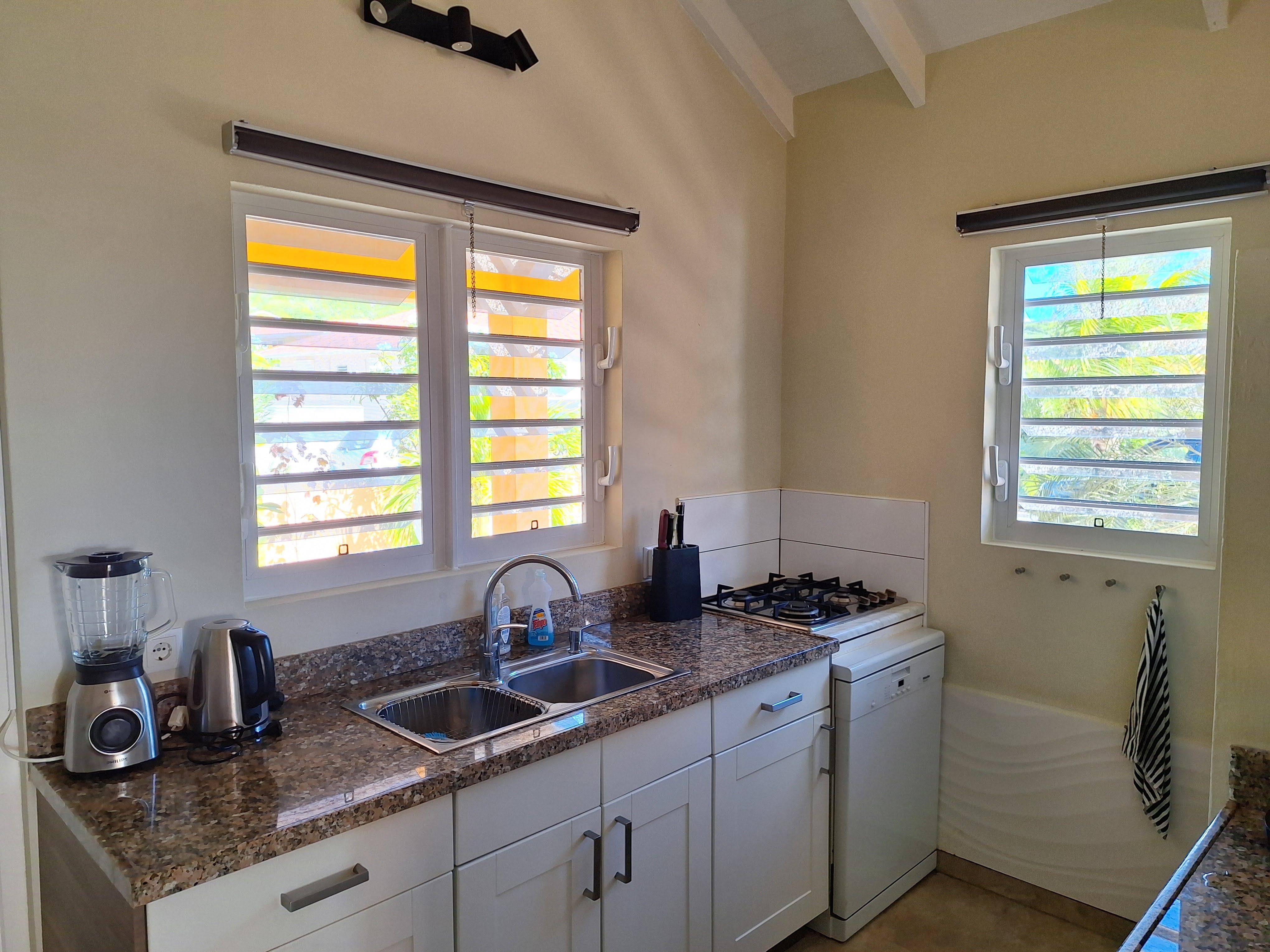 The granite worktop with sink and gas hob in front of the shuttered windows